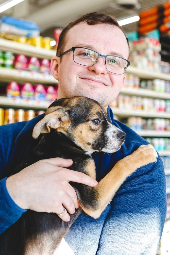 Man Holds Small Dog in Store Aisle